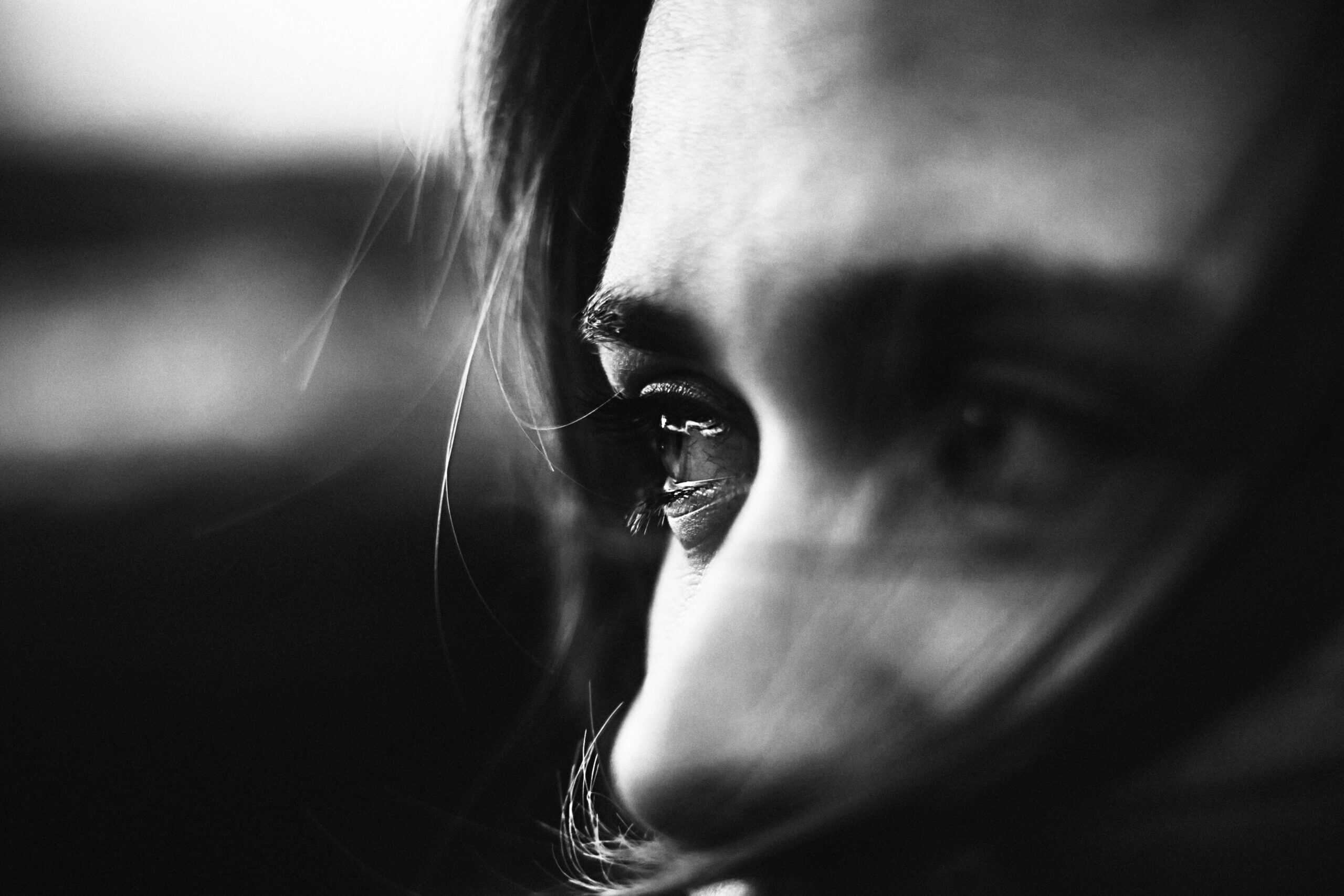 Close-up black and white photo of a woman's eye, highlighting beauty and emotion.