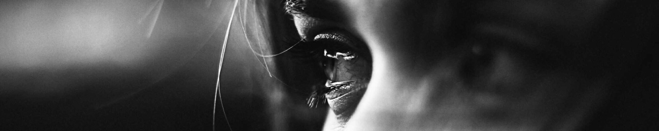 Close-up black and white photo of a woman's eye, highlighting beauty and emotion.