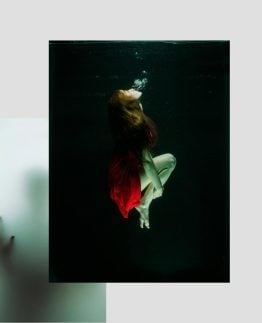 Refined red dress woman underwater, artistic photography, moody and mysterious vibe, fashion and creative concept.