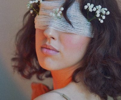 Female model with flowers, blindfolded, in creative and stylish photo.