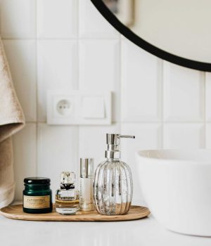 Elegant bathroom with modern accessories and gold fixtures, featuring a white sink, glass soap dispenser, and cozy beige towels.